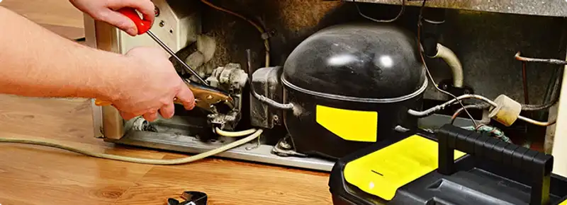 Refrigerator repair technician fixing the compressor and wiring in National City, CA