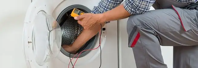 Dryer repair technician inspecting and repairing a clothes dryer in San Diego, CA