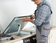 Appliance repair technician installing a built-in cooktop in San Diego, CA