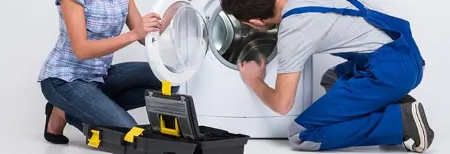 Washer repair technician inspecting a front-load washing machine with tools in San Diego, CA