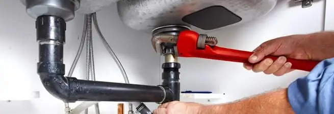 Garbage disposal repair technician tightening the sink drain and disposal connection in San Diego, CA