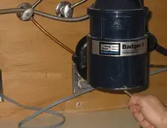 Garbage disposal repair technician tightening the mounting ring under a sink in San Diego, CA
