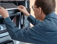 Appliance repair technician replacing a microwave vent filter in San Diego, CA