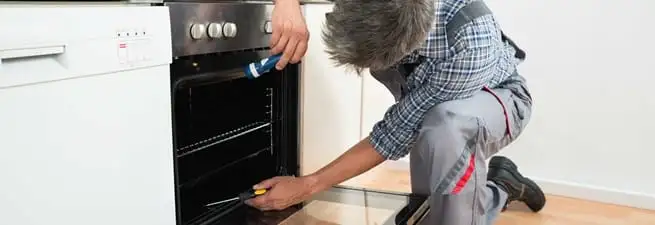 Oven repair technician inspecting and servicing an electric oven in San Diego, CA