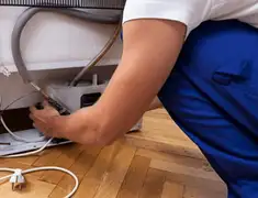 Appliance repair technician fixing refrigerator water line and connections in San Diego, CA