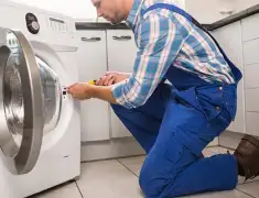 Washing machine repair technician servicing a front-load washer in San Diego, CA