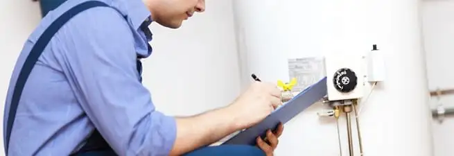 Water heater repair technician inspecting the unit and recording service notes in San Diego, CA