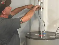 Water heater repair technician tightening supply line connections in San Diego, CA