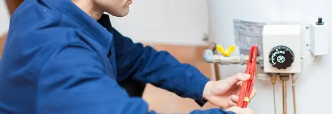 Water heater repair technician adjusting the temperature control and gas valve in San Diego, CA